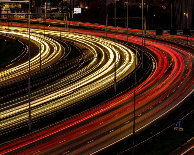 Vele koplampen en achterlampen van het verkeer die in de avond als een sliert over de A16 bij de Van Brienenoordburg slingeren