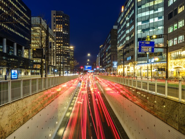 Spitsuur in de avond met vele koplampen en achterlampen die oplichten in Rotterdam tussen de gebouwen in