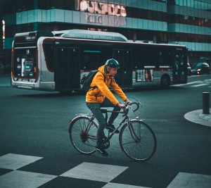 Fietser met oranje kleding die over de weg fietst. Foto via Unsplash gemaakt door Florian Marette