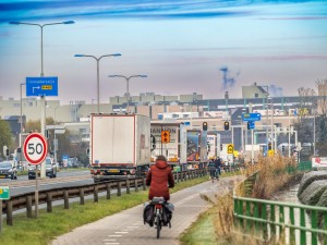 Fietser in de winter op een fietspad naast een autoweg in het Westland